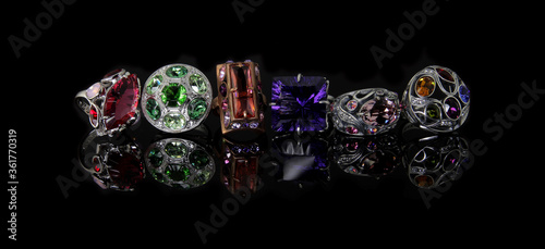 Rings with multi-colored stones on a black reflective background