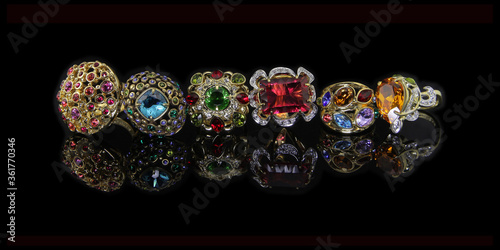 Rings with multi-colored stones on a black reflective background