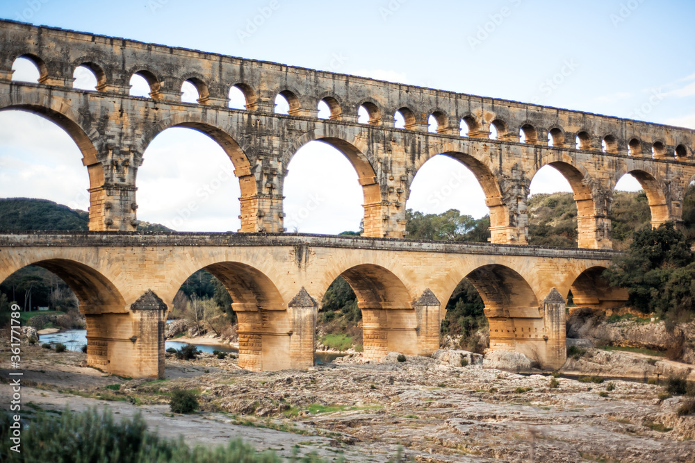 Roman aqueduct Pont du Gard above Gardon river, Unesco World Heritage site. Located near Nimes, Languedoc, France, Europe. Big stone roman arch. Travel tourism destination in Provence.