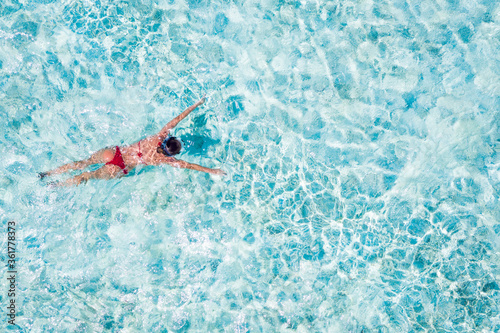 Top above high angle aerial drone view of her she slim fit girl diving under pure blue crystal clean clear ocean water searching looking fish exploring world sunny hot weather mild climate destination