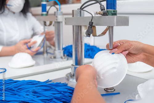 Women work at a machine for the manufacture of medical masks with nanofiber and solder loops to them with ultrasound. Coronovirus and Covid-19 Prevention photo