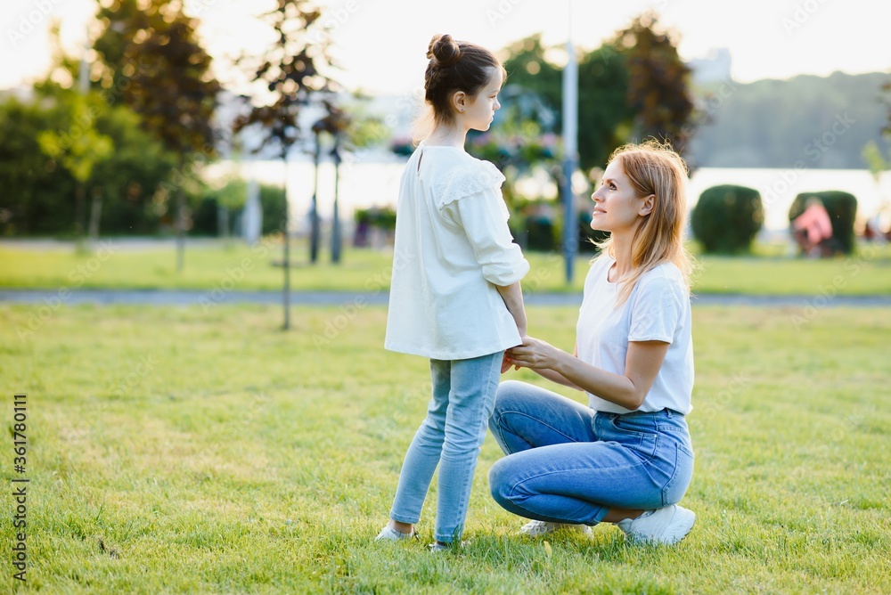 Portrait of mother with daughter in a summer park. Image with selective focus, noise effects and toning. Focus on the girl and mom. Portrait of mother with daughter in a summer park. Image with selective focus, noise effects and toning. Focus on the girl and mom.