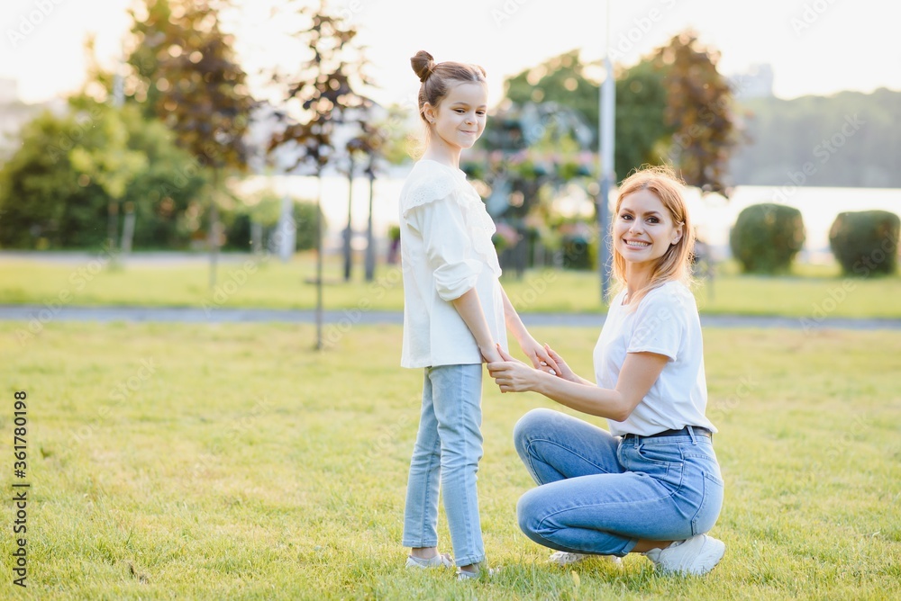 Mother and daughter having fun in the park. Happy family concept. Beauty nature scene with family outdoor lifestyle. Happy family resting together. Happiness and harmony in family life.