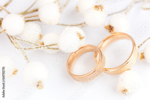 Elegant wedding background - two golden rings and decorations on white background