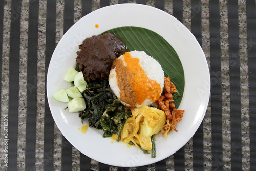 Nasi Padang consisting of white rice, rendang, tempeh orek, and vegetables in a white plate. Indonesian traditional food. Rendang Padang. Spicy beef stew from Padang, Indonesia photo