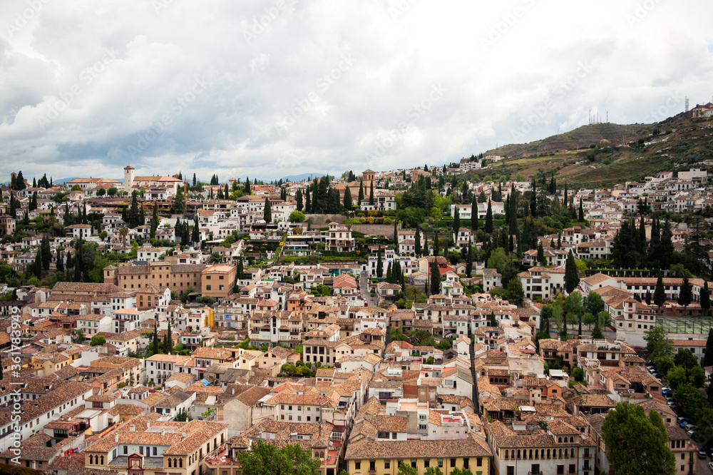 Panoramic view of Granada city from Alhambra castle, Spain, in rainy day with clouds on background. Travel tourism destination.