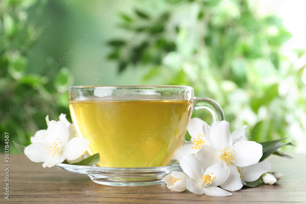 Cup of tea and fresh jasmine flowers on wooden table Cup of tea and fresh jasmine flowers on wooden table