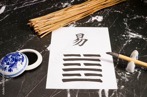 Close up of an I Ching arrangement with the 63th hexagram (After Completition/Chi Chi) written with a chinese ink brush on rice paper. There are also yarrow stalks, and a chinese ink tank. photo