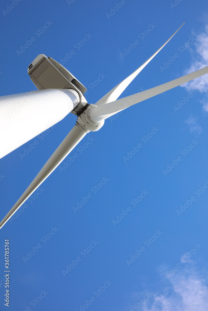 Wind turbine against beautiful blue sky, low angle view. Alternative energy source Wind turbine against beautiful blue sky, low angle view. Alternative energy source