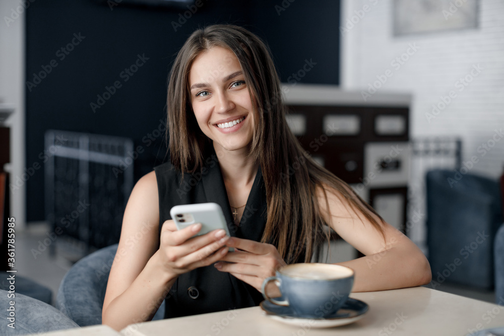 Portrait of a young smiling woman in cafe with coffee cup and phone Portrait of a young smiling woman in cafe with coffee cup and phone