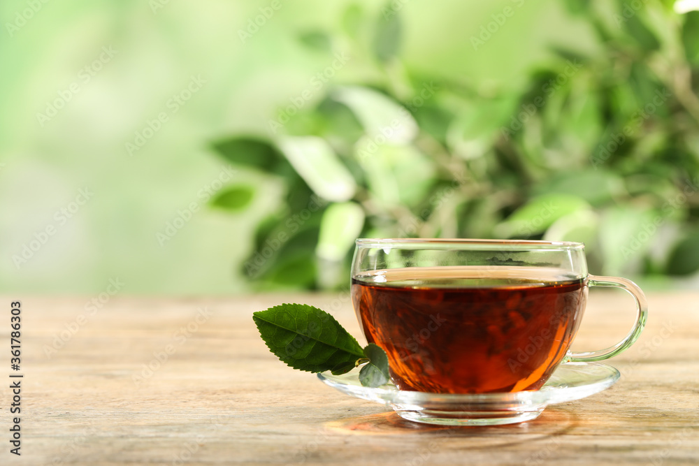 Cup of black tea on wooden table against blurred background. Space for text Cup of black tea on wooden table against blurred background. Space for text