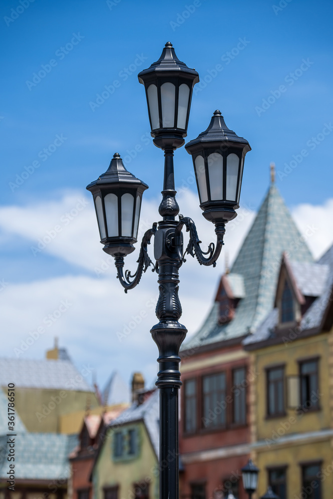 Street lamppost against the old buildings background. Classic victorian street lamps on an old fashioned iron lamp post set