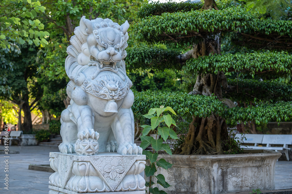 Marble white lion statue in outdoors park in tropical garden, Vietnam Marble white lion statue in outdoors park in tropical garden, Vietnam