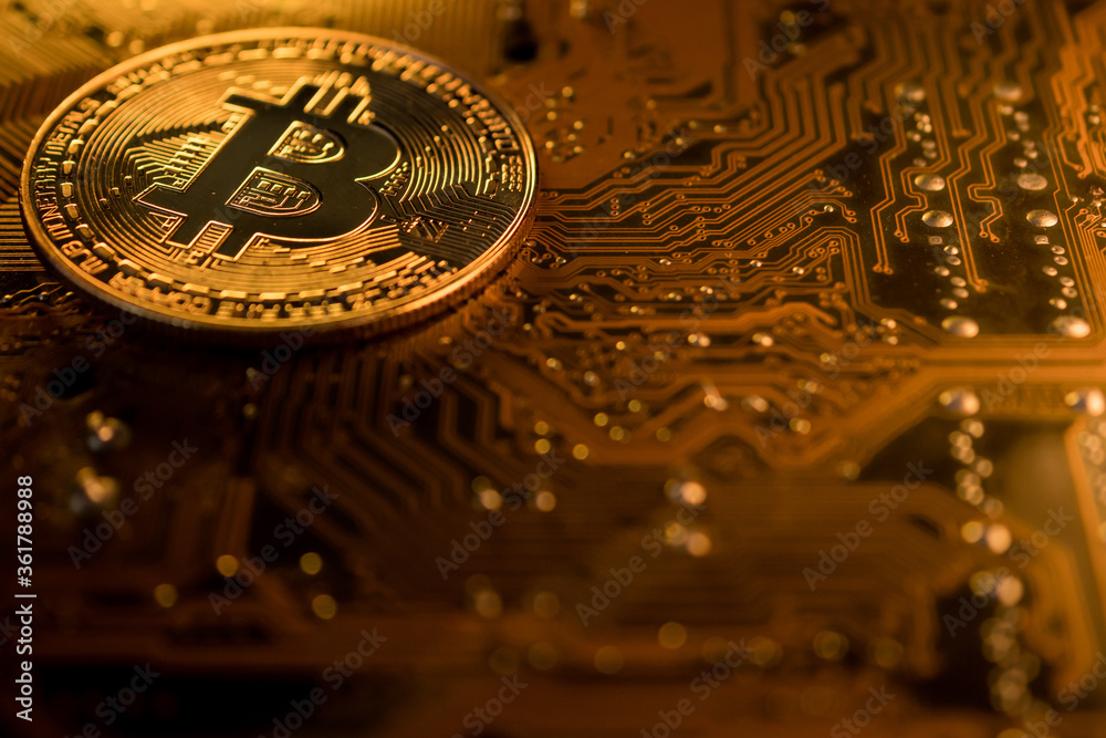Golden coins with bitcoin symbol on a main board computer.