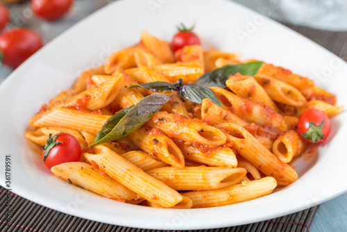 Penne pasta in tomato sauce with chicken, tomatoes decorated with parsley