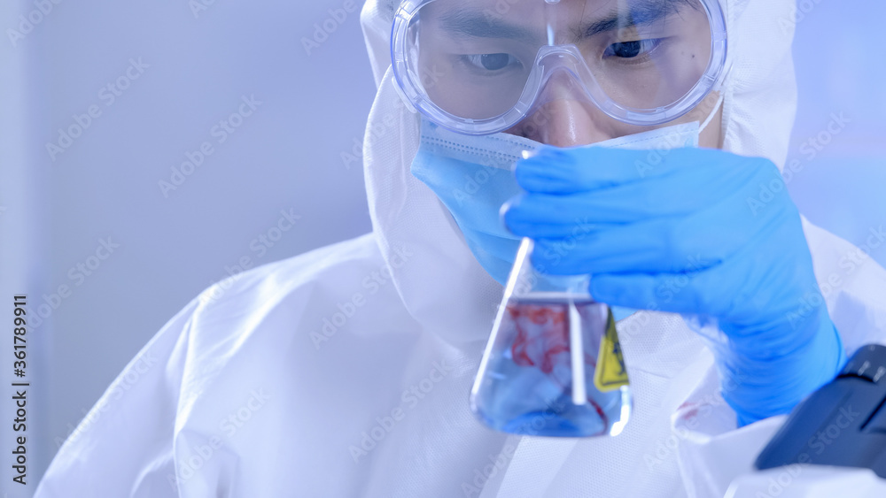 Scientist in PPE suite doing some research checking a liquid in a test tube at laboratory. Scientist in PPE suite doing some research checking a liquid in a test tube at laboratory.