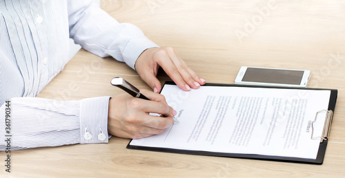 Girl sits at a table and signs a contract. Business