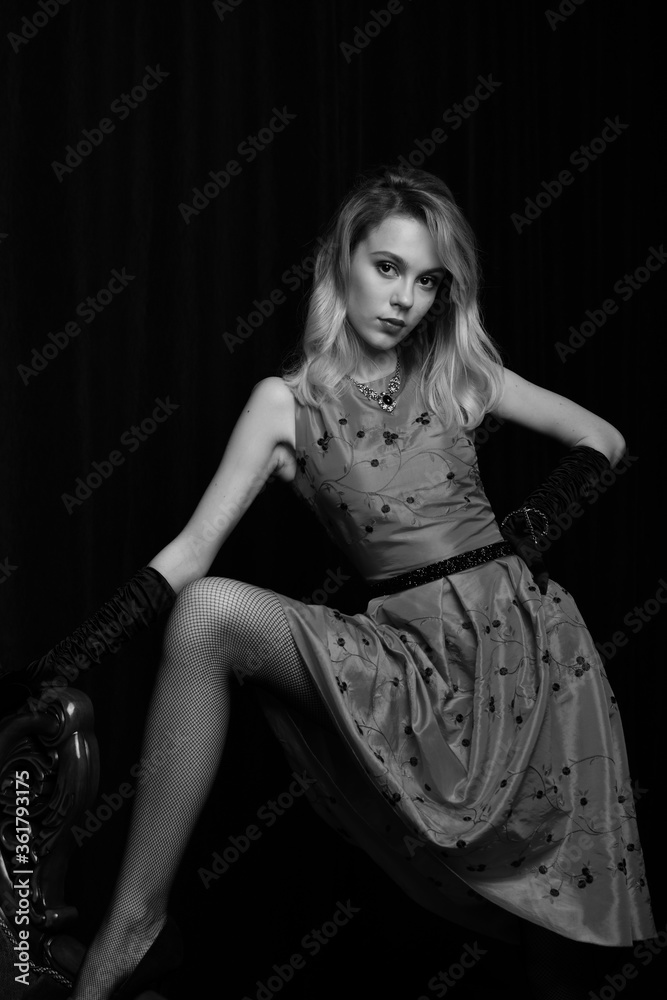 beautiful girl in a red dress posing in a chair in a waiting pose