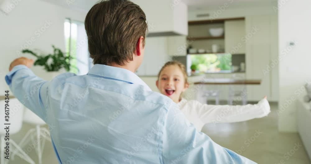 Authentic shot of an young happy smiling father is enjoying time together with his cute little girl in the kitchen. A daughter is giving a hug to a father, they are happy to spend time together. Authentic shot of an young happy smiling father is enjoying time together with his cute little girl in the kitchen. A daughter is giving a hug to a father, they are happy to spend time together.