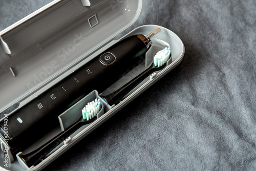Modern black sonic or electric toothbrush in travel case on background with copy space. Concept of professional oral care and healthy teeth by using sonic smart toothbrush