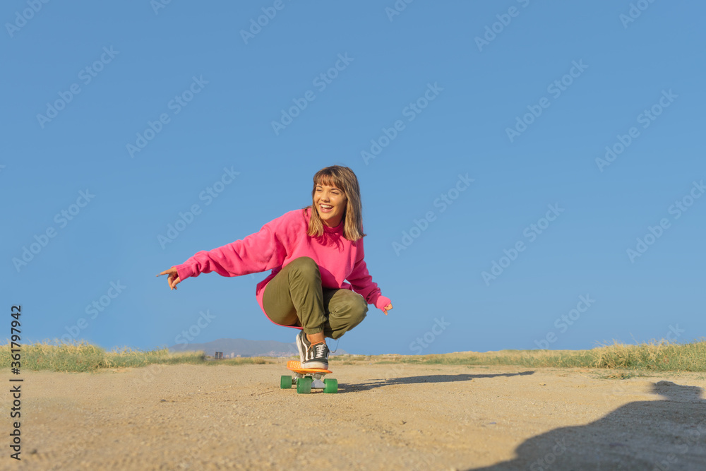 Young woman with pink jersey skateboarding in a footpath Young woman with pink jersey skateboarding in a footpath
