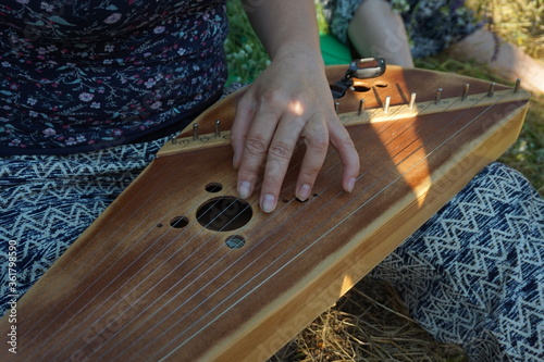 A girl plays a stringed old wooden instrument. photo