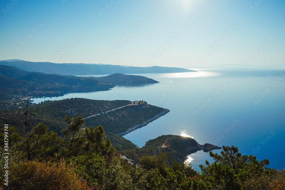 View from the mountain to the beautiful bays of the Mediterranean Sea. Reflection of the setting sun - lunar path. Greece, Halkidiki, Pyrgadikia.