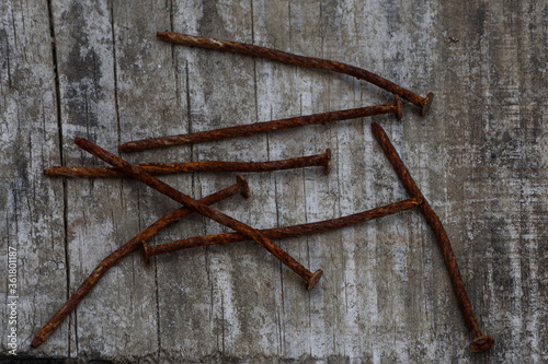 A few rusty crooked nails lie on an old wooden plank