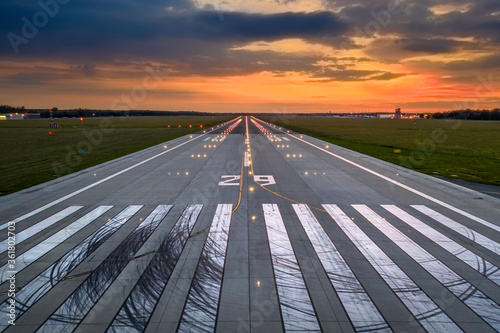 Aerial view on empty airport runaway with markings for landings, 29 and all navigation lights on at the colorful sunset, clear for airplane landing or taking off in Wroclaw  airport
