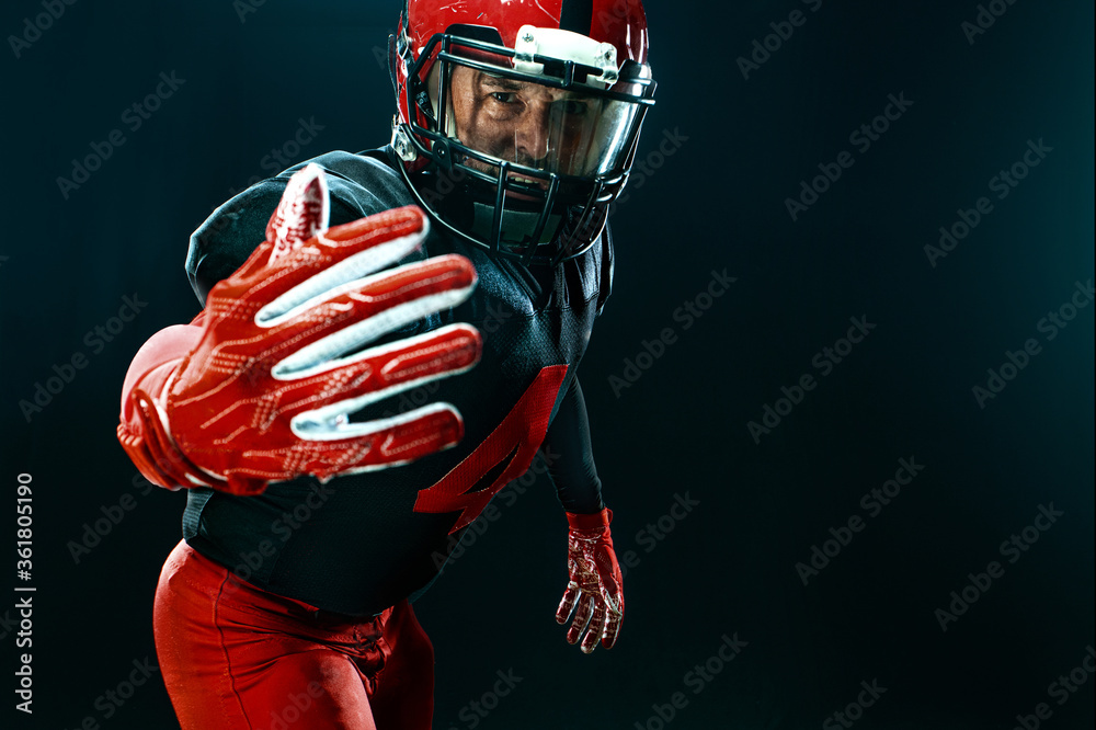 American football player, athlete sportsman in red helmet on black background. Sport and motivation wallpaper. American football player, athlete sportsman in red helmet on black background. Sport and motivation wallpaper.