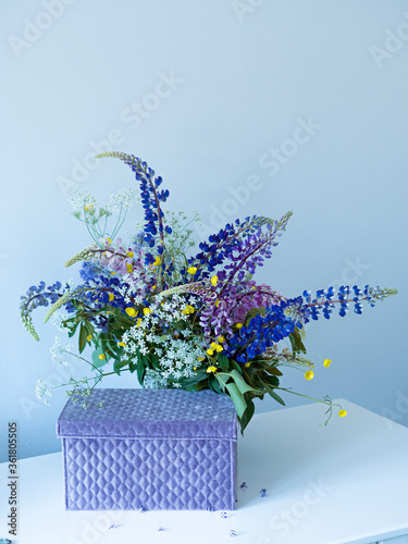Fototapeta Naklejka Na Ścianę i Meble -  Close-up wildflower bouquet in glass vase and beautiful gift box on the white table. White background. Wild flowers at home.