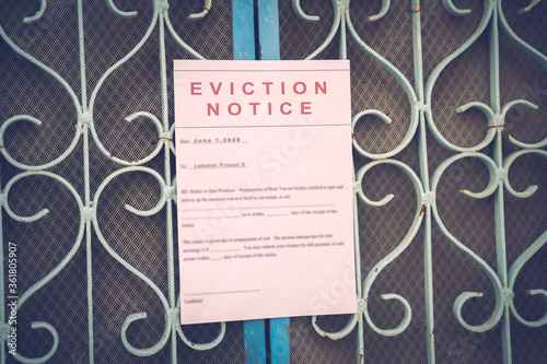 Foreclosed or eviciton notice on a main door with blurred details of a house with vintage filter. photo
