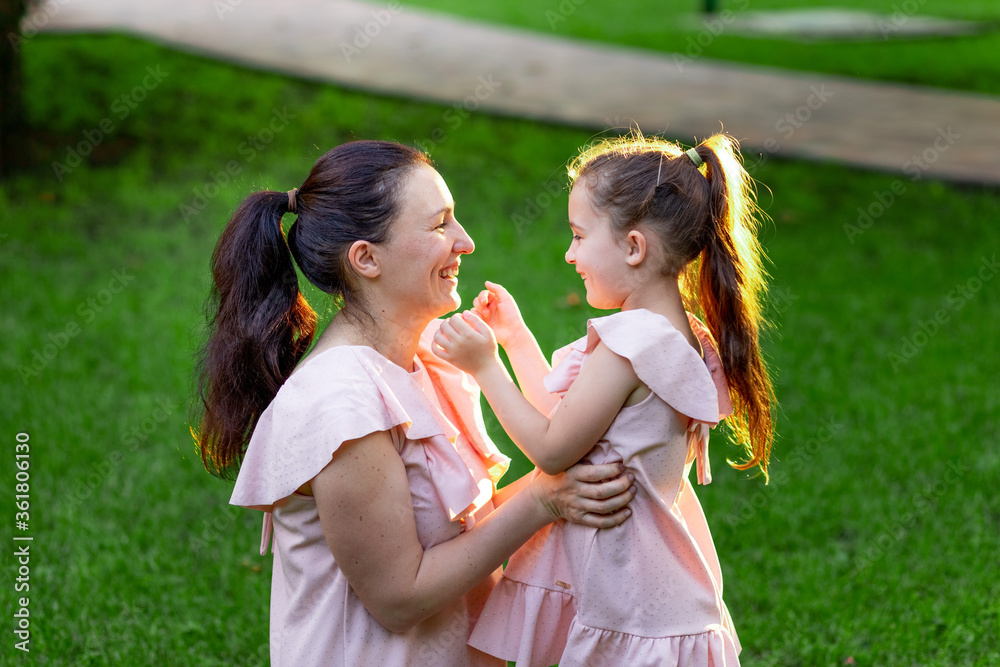 mother and daughter 5-6 years old sit in the Park on the grass in the summer and laugh, mother-daughter conversation, the concept of a happy family, mother-child relationship, mother's Day mother and daughter 5-6 years old sit in the Park on the grass in the summer and laugh, mother-daughter conversation, the concept of a happy family, mother-child relationship, mother's Day