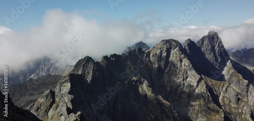 Mountain chain covered in clouds, sunny day.
