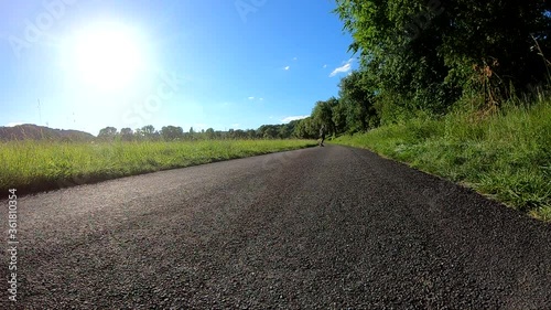 Slow motion shot of skateboarder riding his longboard towards the camera on a country road during a scenic sunset (front-view)