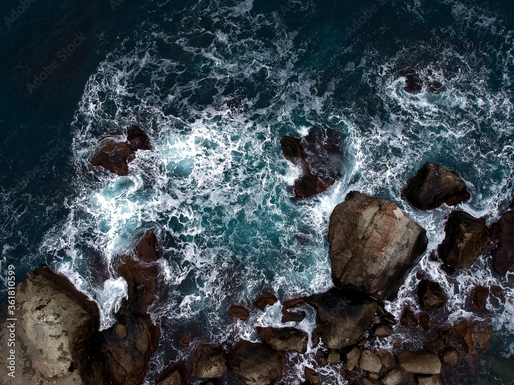View from the height of the waves breaking on the rocks and white foam