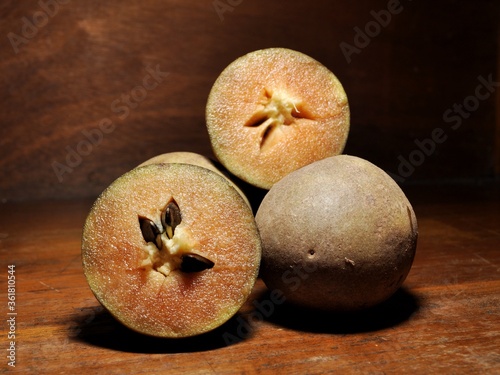 Sawo or Sapodilla isolated on wooden table. Tropical fruit concept