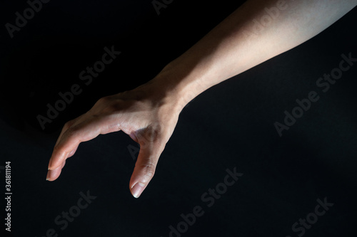 Reaching hand on black background, Right hand of Asian woman, Dark tone