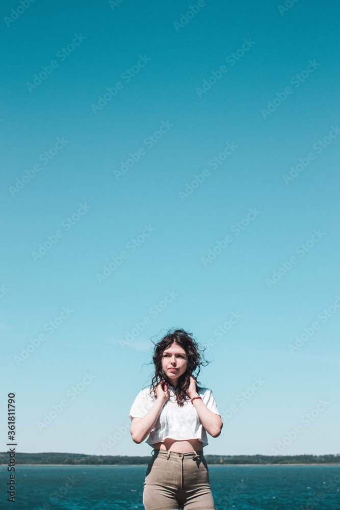 Obraz premium Beautiful happy woman enjoying summer outdoors. Lifestyle concept. Black-haired young woman against the sky.