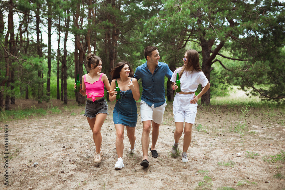 On the way. Group of friends walking down together during picnic in summer forest. Lifestyle, friendship, having fun, weekend and resting concept. Looks cheerful, happy, celebrating, festive. On the way. Group of friends walking down together during picnic in summer forest. Lifestyle, friendship, having fun, weekend and resting concept. Looks cheerful, happy, celebrating, festive.