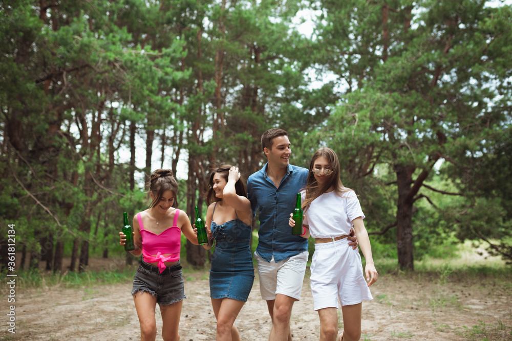 On the way. Group of friends walking down together during picnic in summer forest. Lifestyle, friendship, having fun, weekend and resting concept. Looks cheerful, happy, celebrating, festive. On the way. Group of friends walking down together during picnic in summer forest. Lifestyle, friendship, having fun, weekend and resting concept. Looks cheerful, happy, celebrating, festive.