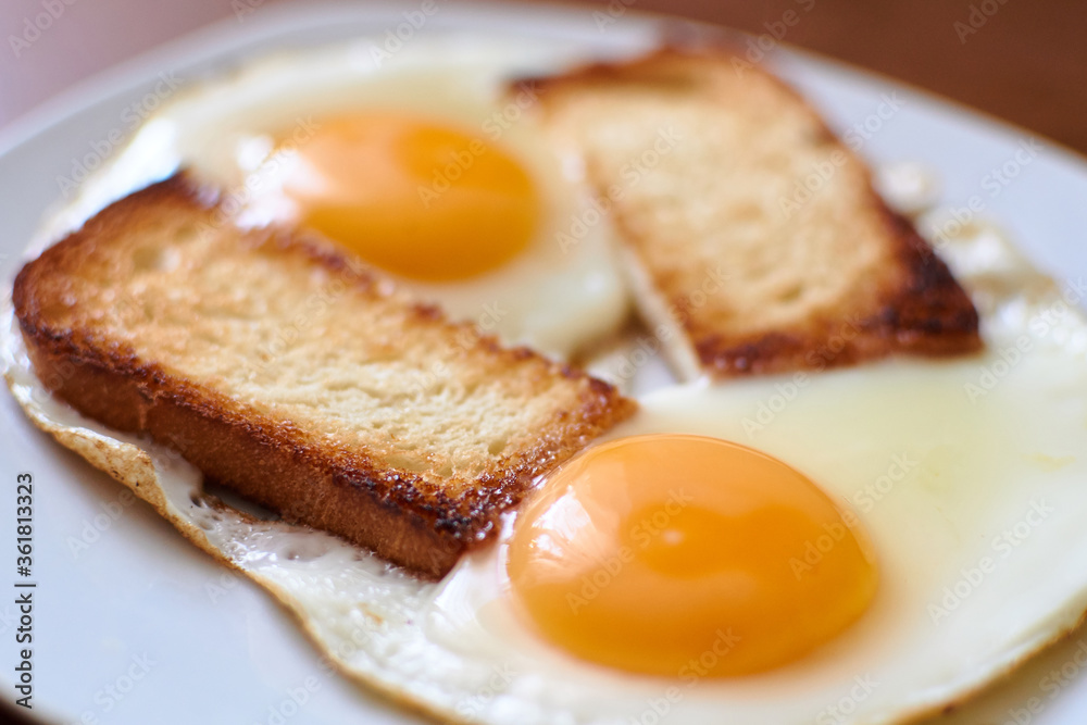 Two fried eggs with toast on a plate. Two fried eggs with toast on a plate.