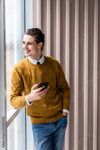 Handsome businessman in formal wear use phone in office