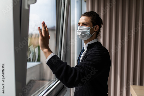 Young businessman in protective mask and look s out the window in office