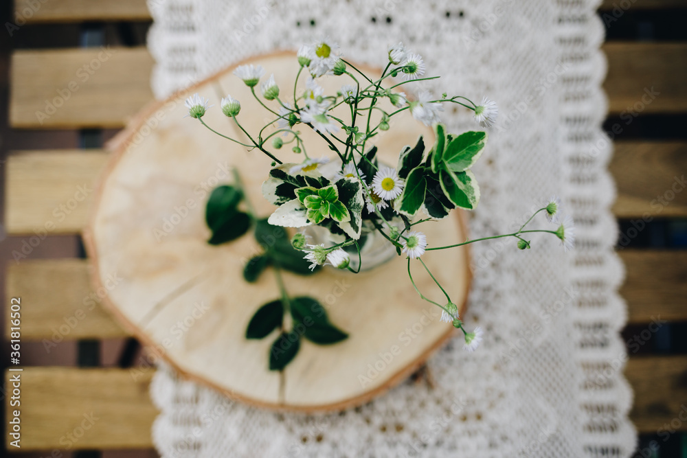 Blumen in einer Vase auf einem Holzbrett auf einer Häkeldecke. Blumen in einer Vase auf einem Holzbrett auf einer Häkeldecke.