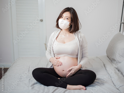  Beautiful asian pregnant woman is wearing protective mask in her home , Coronavirus protection concept