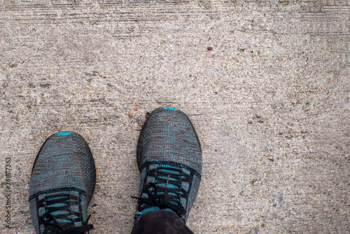 Personal perspective from top view of man standing on concrete Footpath or cement floor.