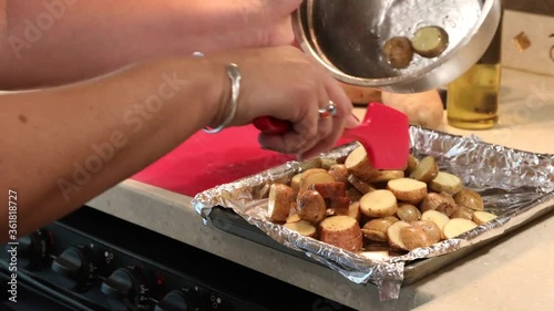 Close up of woman putting sliced, oiled  and seasoned  baby potatoes onto a pan for roasting in an RV kitchen photo
