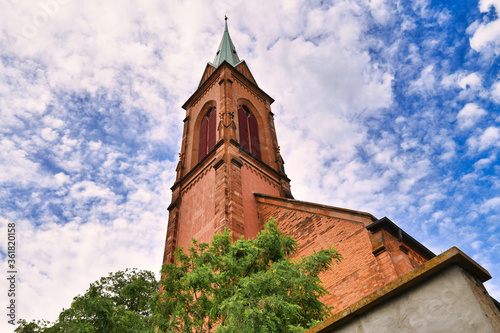 Tower of Protestant church called 'Evangelische Stadtkirche' in front of cloudy blue sky in historical Ladenburg city in Germany