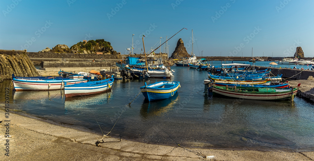 A panorama view of Fishermen's boats against a background of Isole dei Ciclopi at Aci Trezza, Sicily in summer